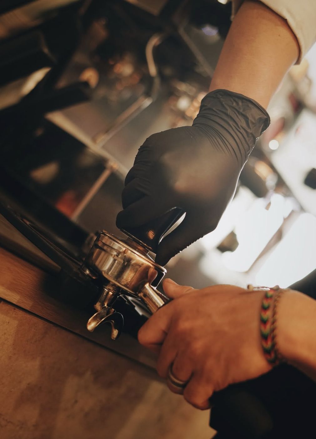 Barista bersarung tangan hitam memasang portafilter espresso