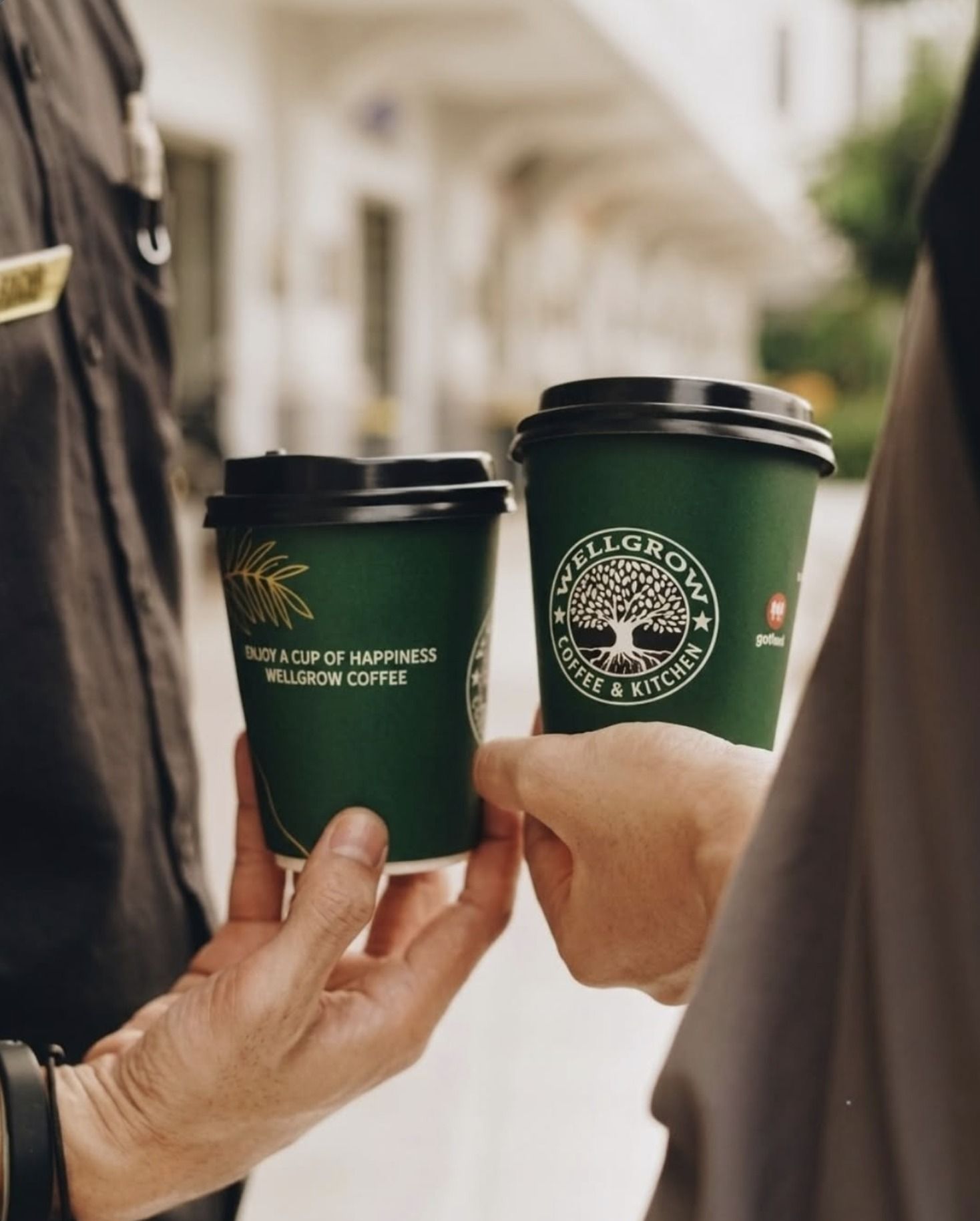 Dua gelas kopi Wellgrow berlogo pohon di tangan pelanggan